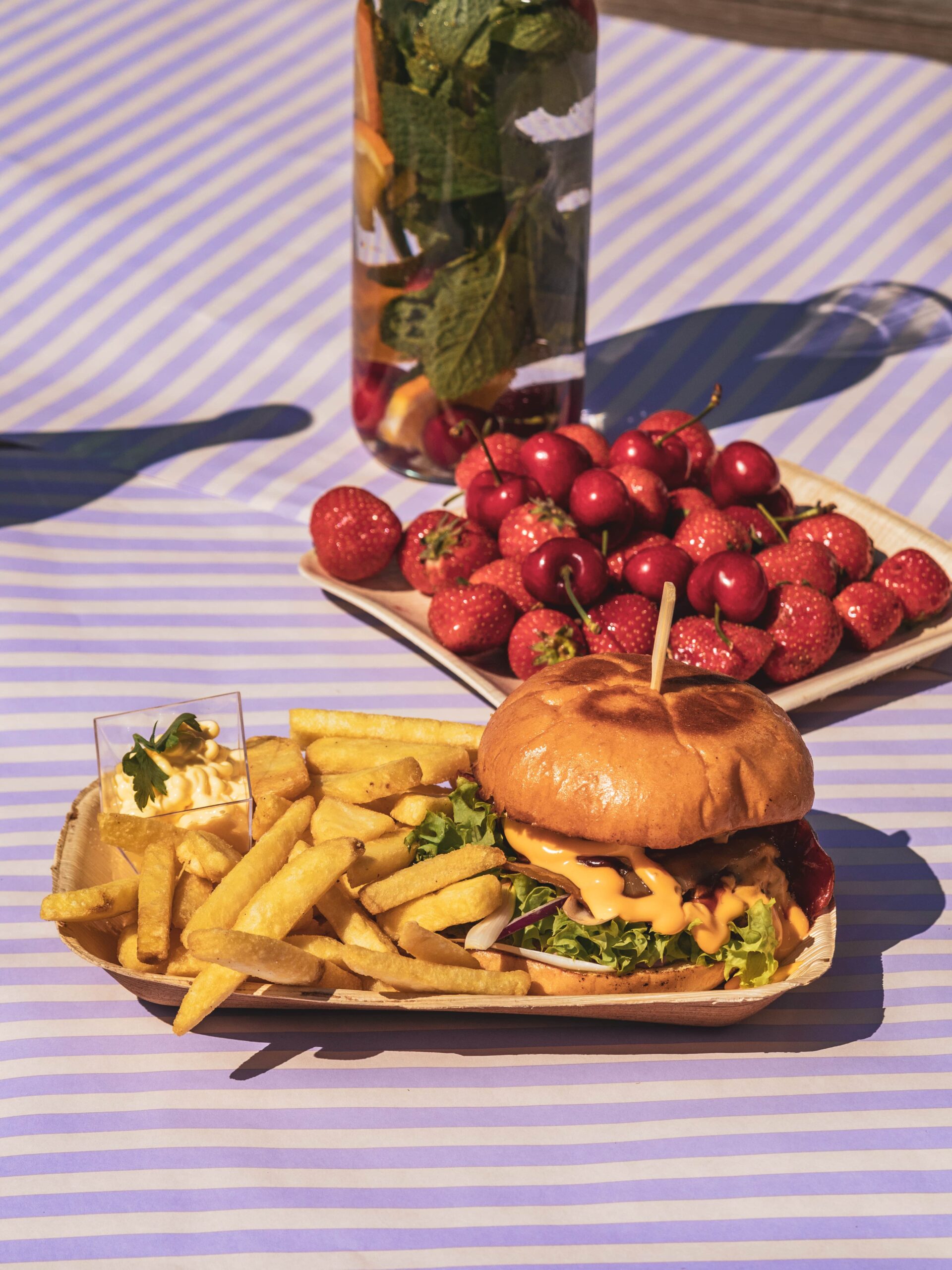 Bord med asjetter med hamburger, pommes frites og jordbær